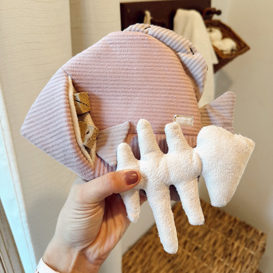 Hand holding an angel fish dog toy indoors.