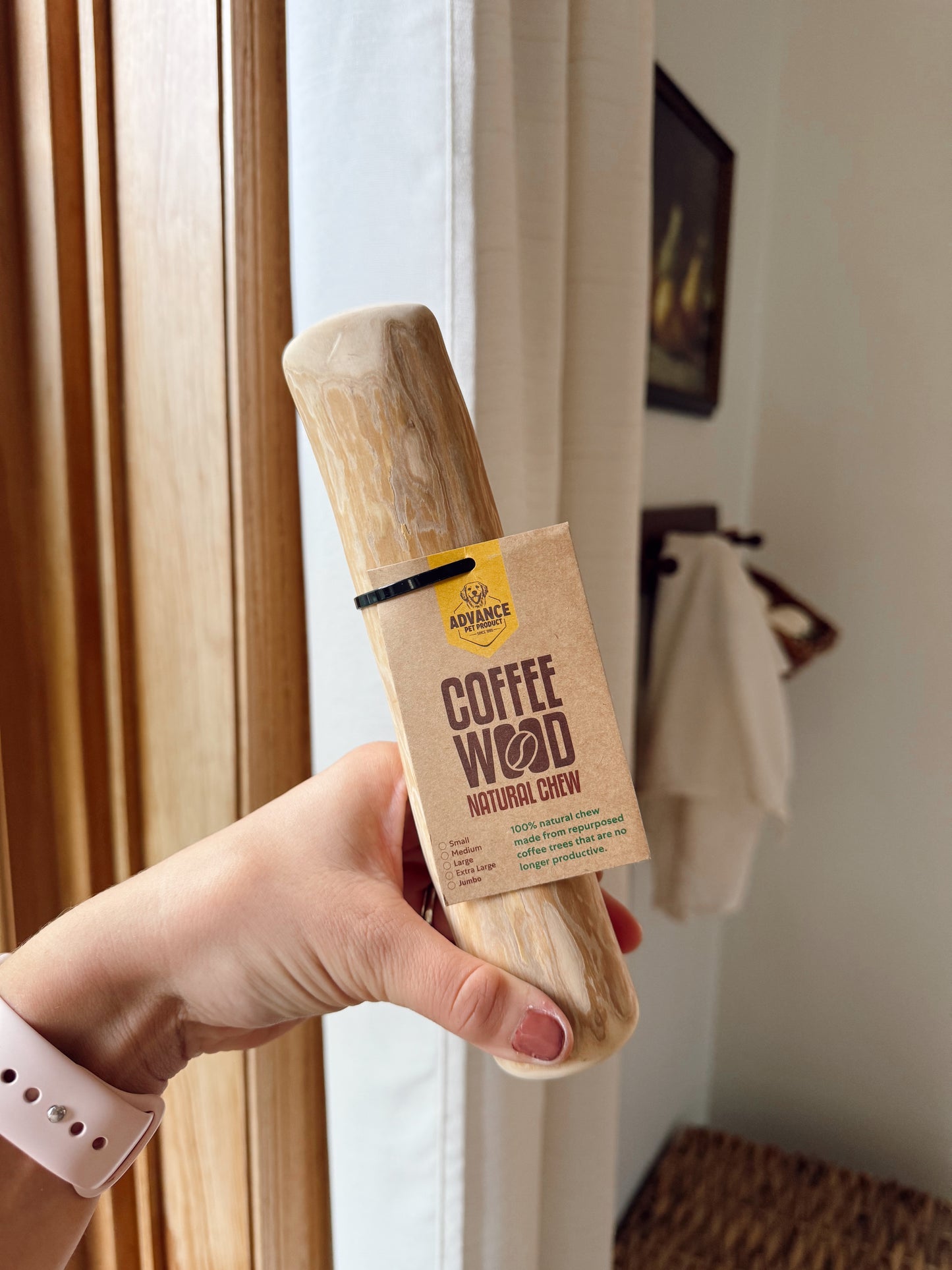 Person holding a wooden product labeled 'Coffee Wood' with a neutral background.
