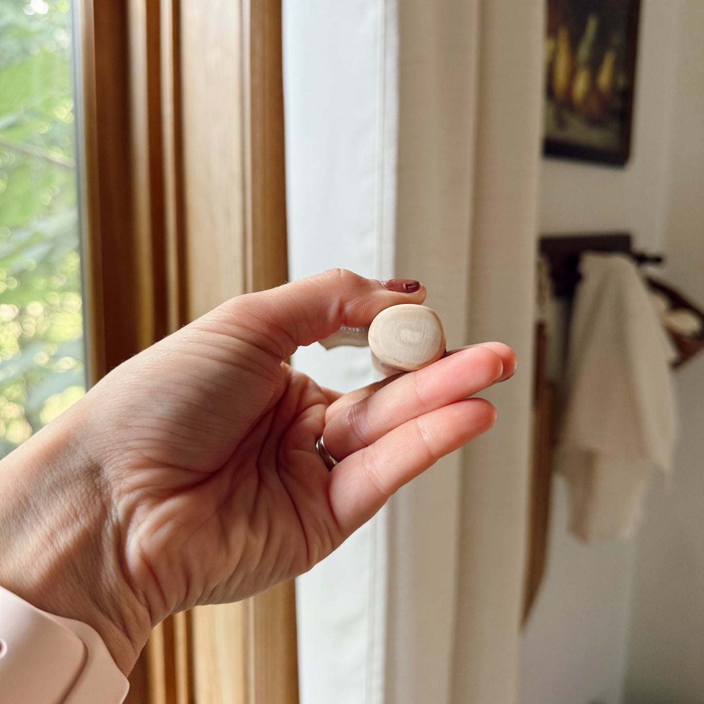 Hand holding a dog coffee wood stick sideways indoors.