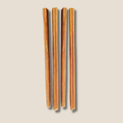 Set of four dog bully sticks on a beige background.