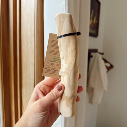 Hand holding a dog coffee wood stick indoors.