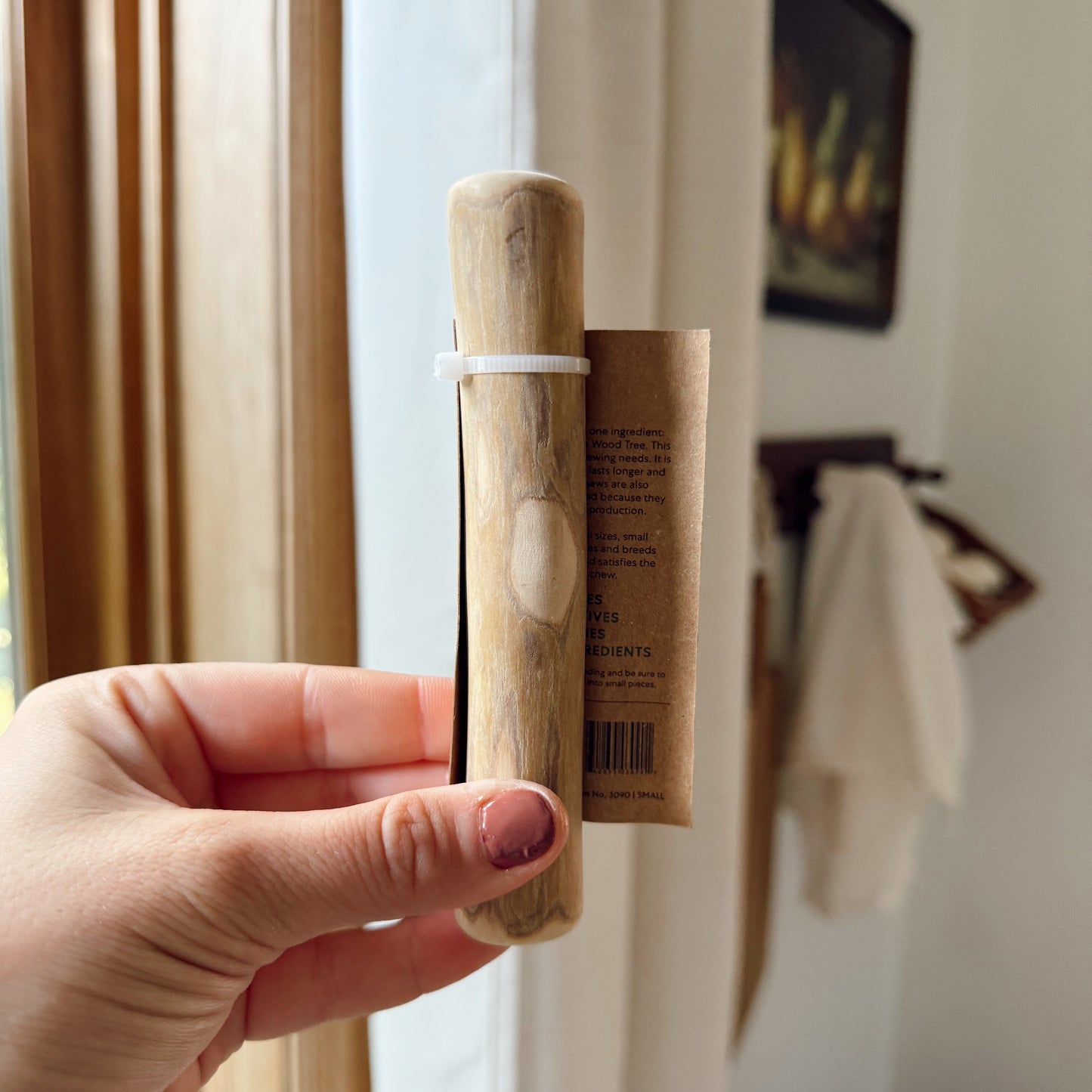 Hand holding a small dog coffee wood stick indoors.