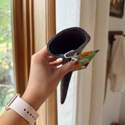 Person holding a black water buffalo horn with a green label indoors.