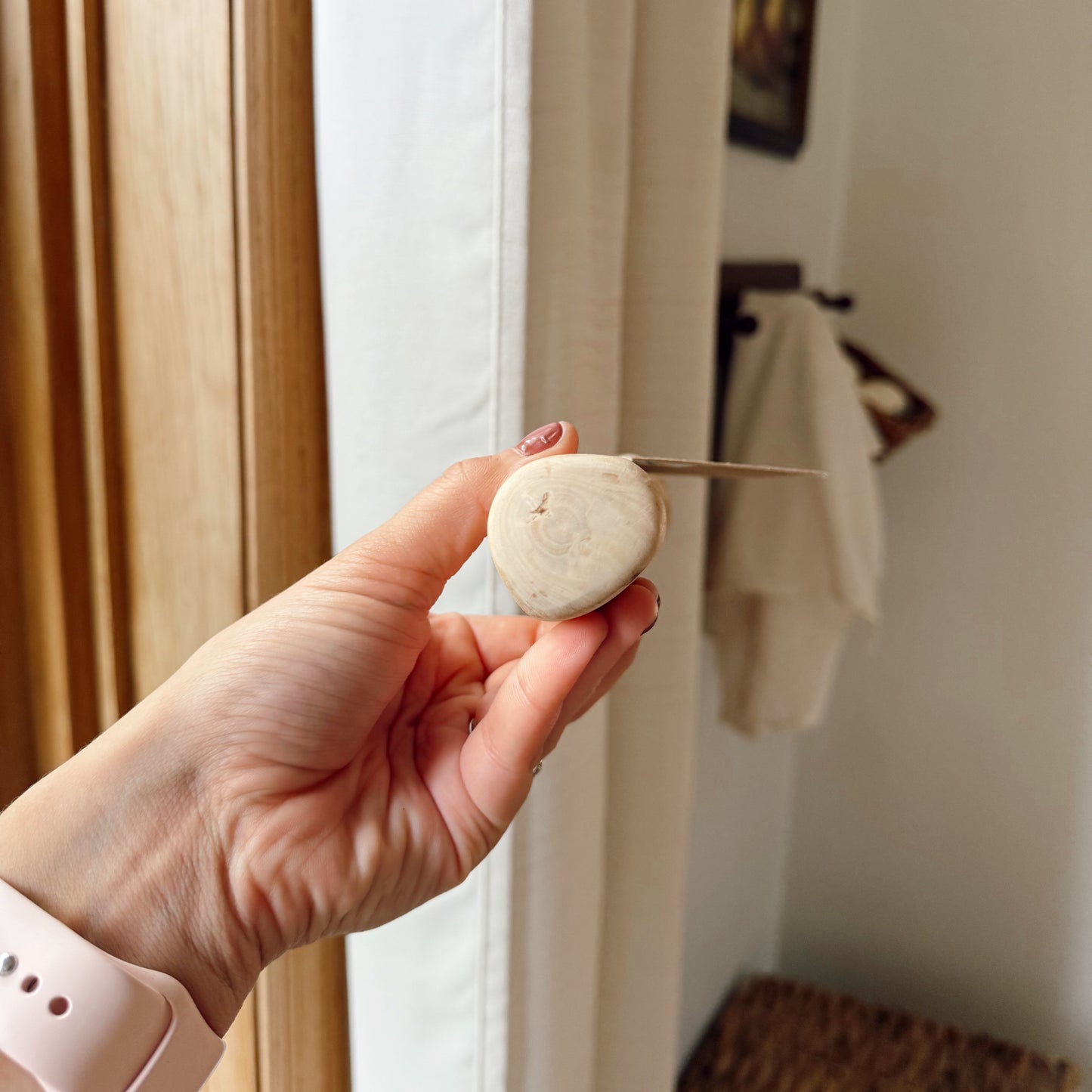 Hand holding a dog coffee wood stick sideways indoors.