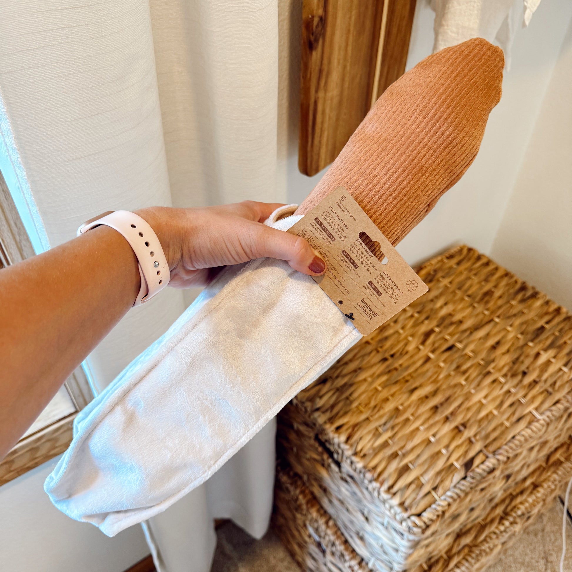 Hand holding a baguette dog toy indoors.