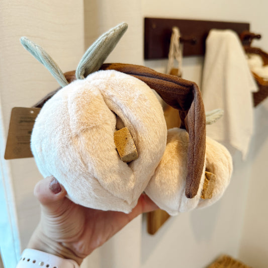 Hand holding a peaches dog toy with treats in it.