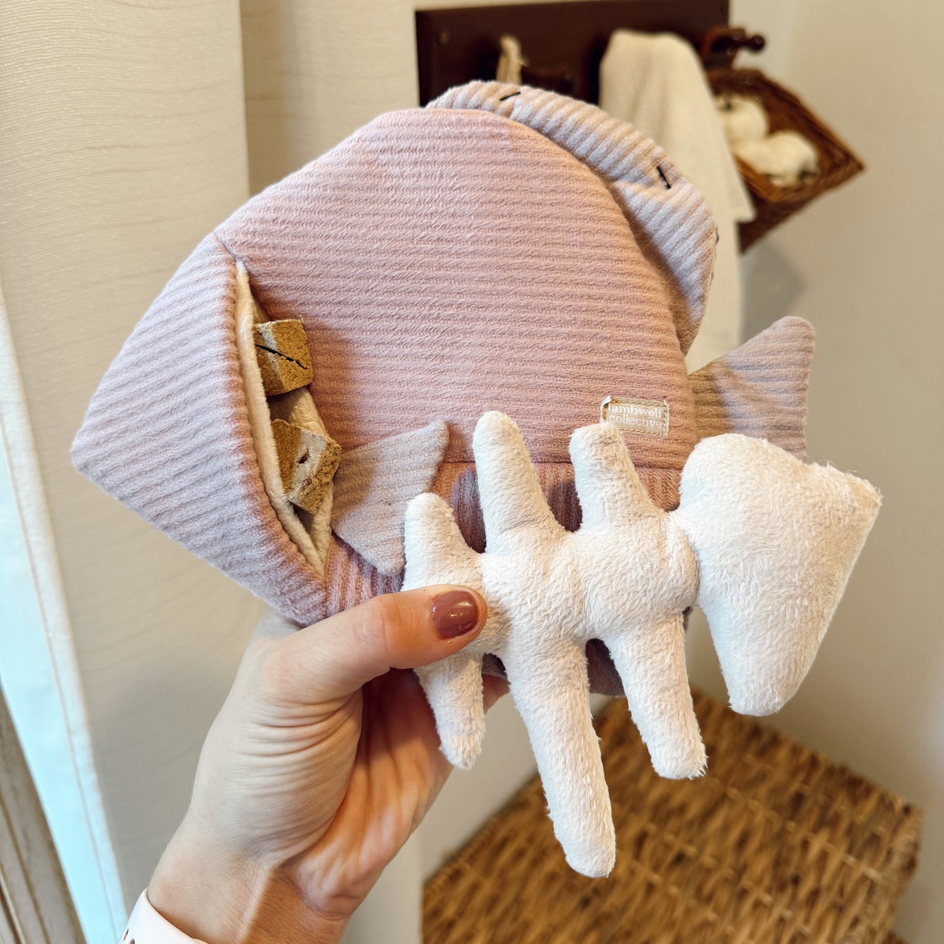 Hand holding an angel fish dog toy indoors.