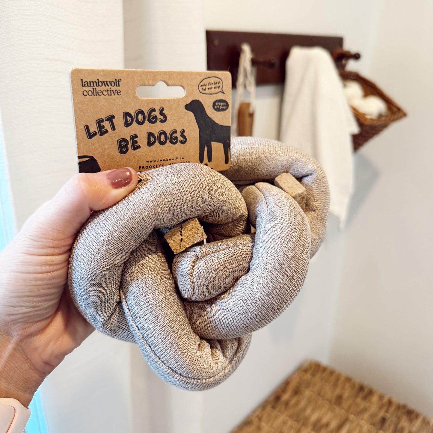 Hand holding a knot dog toy with treats in it indoors.